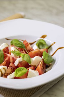 Mozzarella, fesleğen ve balzamik kremalı domates salatası.