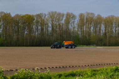 Tractor with sprayer during spring work on the field