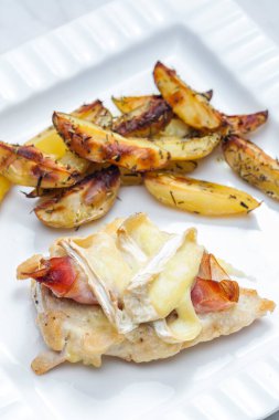 Parma jambonlu tavuk eti ve kızarmış patatesle servis edilen peynirli peynir.