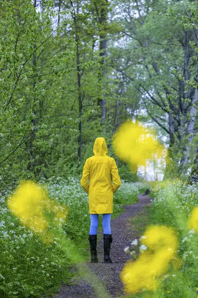 春の自然で黄色のレインコートとゴムブーツを持つ若い女性 — ストック写真