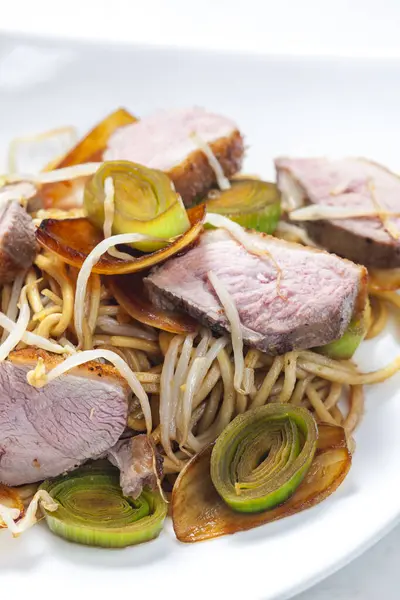 slices of duck breast with noodles, vegetables and bamboo shoots