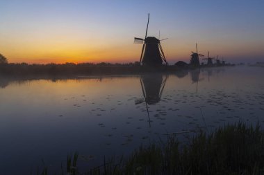 Hollanda 'nın Kinderdijk şehrinde güneş doğmadan hemen önce renkli gökyüzü olan geleneksel Hollanda yel değirmenleri
