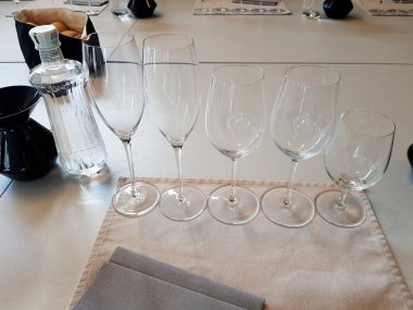 Macaristan 'ın Somlovasarhely şehrinde şarap tatma etkinliğine hazır bir şişe su ve peçeteyle bir masanın üzerine boş şarap kadehleri yerleştiriliyor.