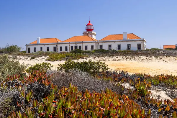 Güneşli bir günde Portekiz 'in Odemira şehrinde yer alan kırmızı ve beyaz kulesiyle Cabo Sardao Deniz Feneri' nin manzarası.