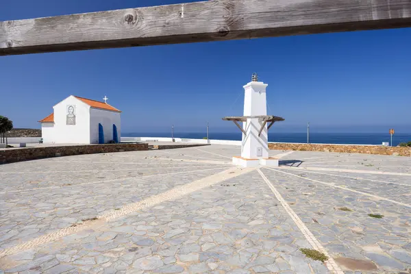 Beyaz bir şapelin manzarası ve Zambujeira do Mar 'daki Atlantik Okyanusu' na bakan asfalt bir karenin navigasyon sinyali.