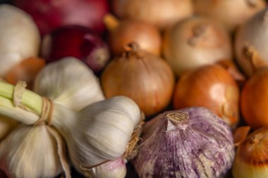 Çeşitli soğan ve sarımsak soğanlarının kapanışı, mutfak ve tarım temaları için ideal olan doğal renklerini ve dokularını sergiliyor