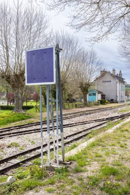 Bligny sur Ouche, Bourgogne Franche Comte, Fransa 'da terk edilmiş eski bir demiryolunun paslı raylarının yanında duran mor metalik tabela.