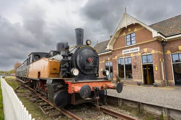 Hollanda, Friesland 'daki Marrum Westernijkerk istasyonunda bulutlu bir gökyüzünün altında park edilmiş klasik buhar treni.