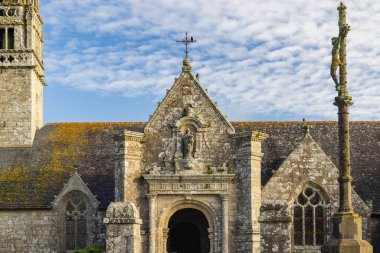 Beuzec Cap Sizun, Brittany 'nin tarihi bir simgesi olan Notre Dame de la Clarte Kilisesi' nin etkileyici yüzü, karmaşık mimarisini ve dini önemini gözler önüne seriyor.