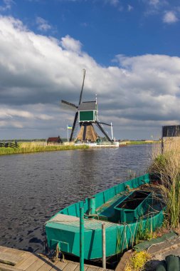 Hollanda 'nın Groot Ammers, Hollanda' da demirlemiş bir teknesi olan bir kanalın manzaralı yel değirmeni manzarası, Hollanda mirası ve manzarası sergileniyor