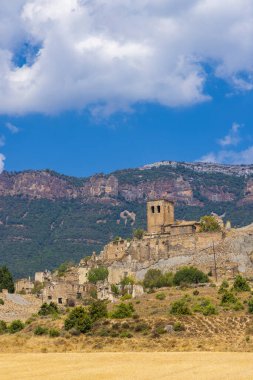 Eski Sigues köyünün kalıntıları bir tepenin üzerinde duruyor. Arkasında Pirene Dağları yükseliyor. İspanya 'nın Aragon bölgesinde.