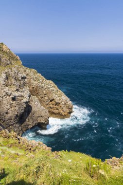 İspanya 'nın Cantabria kıyı şeridinin manzarası güneşli bir yaz gününde kayalıklara vuran dalgalar