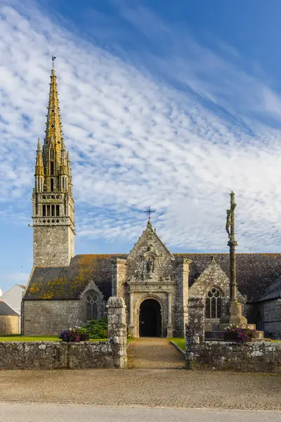 Notre Dame de la Clarte Kilisesi Beuzec Cap Sizun, Finistere, Brittany 'de bulutlu bir gökyüzüne doğru yükselen etkileyici çan kulesiyle