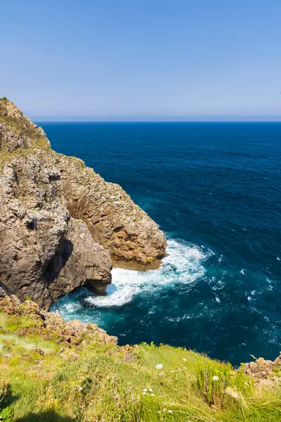 İspanya 'nın Cantabria kıyı şeridinin manzarası güneşli bir yaz gününde kayalıklara vuran dalgalar