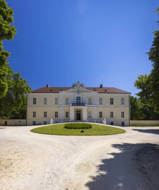 Aşağı Avusturya 'daki Wilfersdorf Sarayı' nın Neoklasik cephesi temiz mavi bir gökyüzünün altında, iyi korunmuş bir çimenlik ve çakıl yolu ile çevrili.