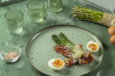 Kızarmış pastırmalı yeşil kuşkonmaz, haşlanmış yumurta ve tabakta parmesan peyniri, sağlıklı ketojenik kahvaltı ya da atıştırmalık