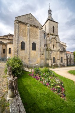 Fransa 'nın Poitiers kentindeki Saint Hilaire Büyük Kilisesi' nin önünde bulutlu bir gökyüzünün altında renkli çiçeklerle çiçeklenmiş.