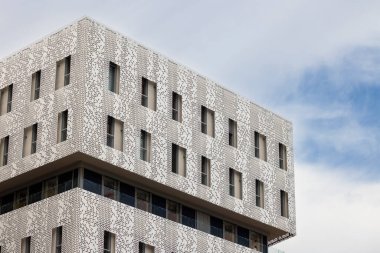Dekoratif desenli ve pencereli modern bir binanın beyaz cephesi Montpellier, Fransa 'da yenilikçi bir mimari sergiliyor.