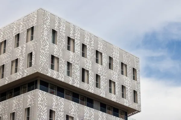 Dekoratif desenli ve pencereli modern bir binanın beyaz cephesi Montpellier, Fransa 'da yenilikçi bir mimari sergiliyor.