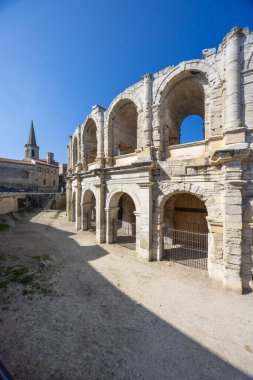 Arles, Fransa 'daki Roma amfitiyatrosu güneşli bir günde kemerleri ve antik mimariyi gösteriyor.