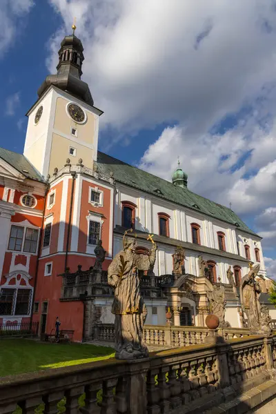 Broumov Manastırı, tarihi bir Benedikt manastırı, dini heykeller ve dinamik bir gökyüzünün zeminiyle vurgulanan barok mimarisi, uzun ve heybetli duruyor.