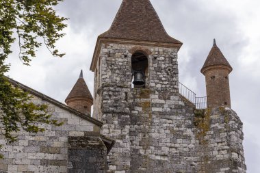 Konik çatıları, taş duvarları ve Fransa Auvillar 'da bulutlu bir gökyüzü olan kilise çan kulesinin mimari ayrıntıları.