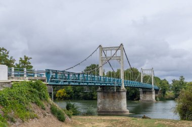 Auvillar, Occitanie 'deki Garonne Nehri' nden geçen metal asma köprü. Fransa 'nın güneybatısında bulutlu bir gökyüzünün altında büyüleyici bir köy.
