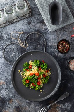 Kavrulmuş brokoli ve kırmızı biberle tatlandırılmış kuskus gurme yemeği, koyu arkaplanda üst görünüm.