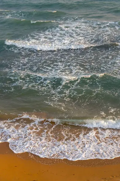 Yumuşak dalgalar nazikçe altın kumlu kıyıya vuruyor dingin ve huzurlu bir sahil manzarası yaratıyor