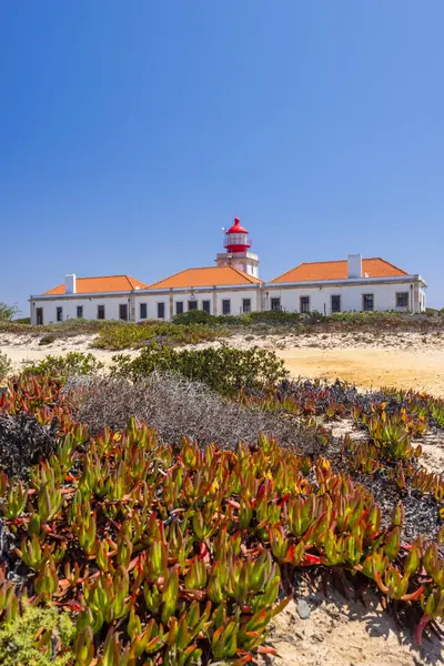 Güneşli bir günde Portekiz 'in Odemira şehrinde yer alan kırmızı ve beyaz kulesiyle Cabo Sardao Deniz Feneri' nin manzarası.