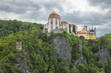 Vranov nad Dyji Şatosu, bulutlu bir gökyüzünün altında, yemyeşil bitki örtüsüyle çevrili, Çek Cumhuriyeti 'ndeki bir uçurumda duruyor.