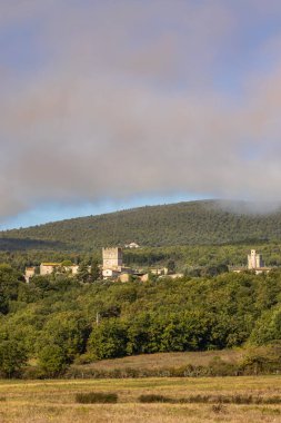 İtalya 'nın Toskana kentindeki ortaçağ Monteriggioni köyü yemyeşil ve dağ zirvesini kaplayan bulutlarla çevrili.