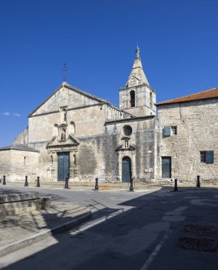 Tarihi Saint Trophime Kilisesi Roma mimarisini açık mavi gökyüzü altında sergileyerek Fransa 'nın Arles şehrinde dimdik ayakta duruyor.