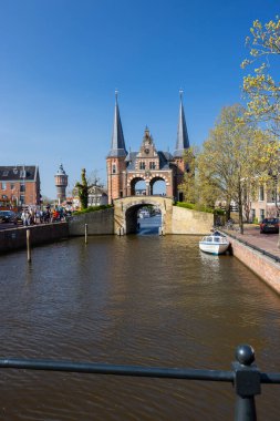 Sneek, Friesland 'daki ikonik Waterpoort kapısının manzarası güneşli bir günde kanalda yelken açan bir tekne.