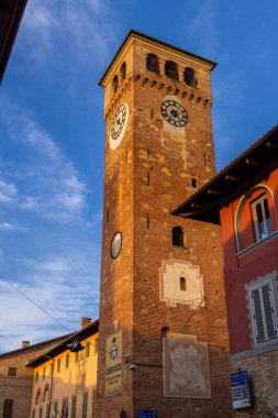 Piedmont, İtalya 'daki Cherasco' nun tarihi saat kulesi, şehrin zengin tarihinin bir kanıtı olan öğleden sonranın altın ışığında güneşleniyor.