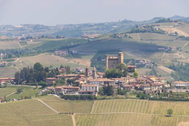 Kuzey İtalya 'nın Piedmont bölgesindeki Langhe bölgesindeki üzüm bağlarıyla çevrili ortaçağ şatosuyla Monforte d' Alba köyünün manzarası.