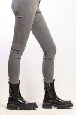 Moda mankeni, şık siyah çizmeleri, büyük topuk tabanlı, gri dar kotlu, modern ayakkabılı ve giyimli.