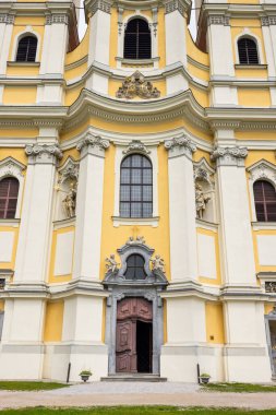 Jasov, Slovakya 'daki Jasov Manastırı' nın ana girişinde kısmen açık ahşap bir kapı, karmaşık taş oymalar ve dini figürlerin heykelleri yer alıyor.