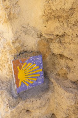 Sarı deniz tarağı kabuğu, Castrojeriz, Burgos, Kastilya ve Leon İspanya 'da taş bir duvara gömülü Camino de Santiago' nun sembolü.