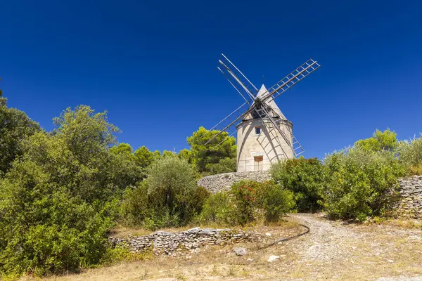 Saint Saturnin les Apt, Provence yakınlarındaki Fransız kırsalındaki ağaçların üzerinde geleneksel yel değirmeni yükseliyor.