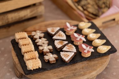 Tahta bir tabakta farklı şekillerde ve kremalı çeşitli noel kurabiyeleri var.