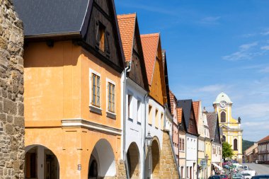 Ustek 'teki geleneksel Çek mimarisi, açık mavi gökyüzünün altında, kemerli girişleri ve uzak bir kilise kulesi olan bir dizi canlı ev içeriyor.