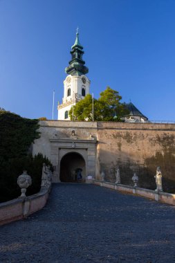 Parke yolu Nitra Kalesi 'nin kemerli girişine çıkıyor. Arka planda heykeller ve Aziz Emmeram Katedrali var. Nitra, Slovakya.
