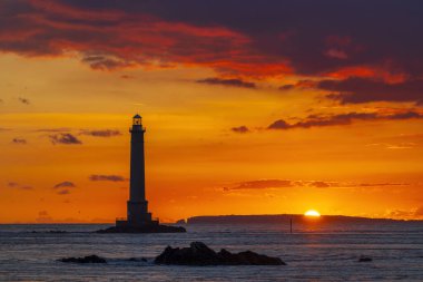 Normandiya, Fransa 'da Phare de la Hague deniz feneri silueti ile okyanus üzerinde turuncu ve mor gün batımı
