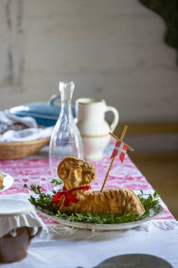 Danimarka bayrağı, boxwood ve kırmızı kurdeleyle süslenmiş kuzu şekilli paskalya pastası Kourim, Çek Cumhuriyeti 'nde masaya bırakılmış sürahi ve sürahi ile servis edilir.