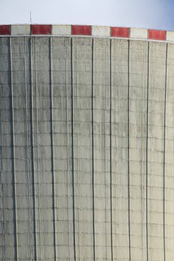 Üzerinde kırmızı ve beyaz çizgiler olan bir nükleer santralin soğutma kulesinin beton yapısı