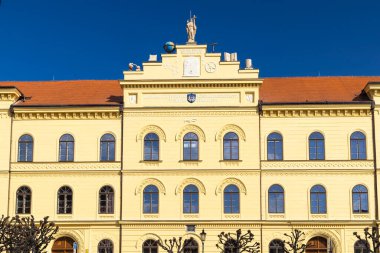 Çekoslovakya 'nın Pisek kentinde yer alan J. K. Tyl Tiyatrosu, açık mavi gökyüzü altında sarı cephesini, kemerli camlarını ve alegorik heykellerini sergiler.