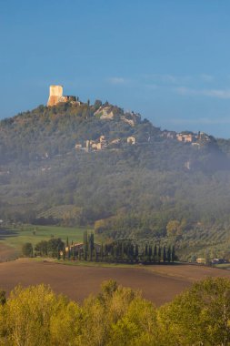 Rocca di Tentennano sisli ve canlı yeşilliklerle Toskana manzarasına bakıyor