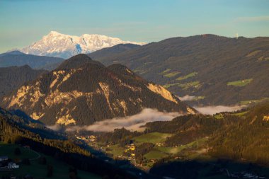 Majestic Dachstein Buzulu, Avusturya 'nın Schladming kentinde nefes kesen bir sonbahar manzarası yaratarak sabah sisi ile kaplanmış pitoresk bir vadiden yükseliyor.