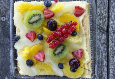 Kremalı meyveli tart kivi, çilek, kırmızı frenk üzümü, yabanmersini, ananas ve şeftali gibi renkli taze meyveler sergileniyor